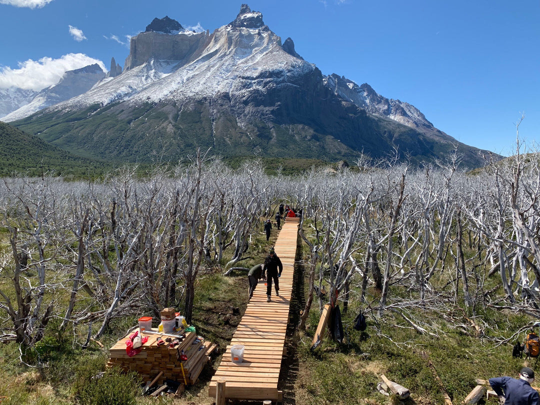 Adventure Travel Fund volunteers building a bridge in a scenic mountainous landscape.
