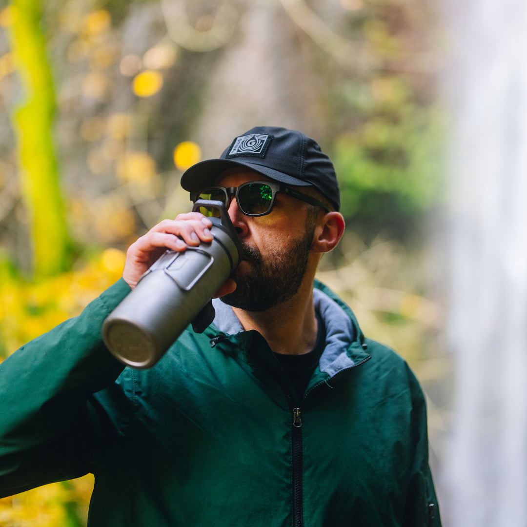 Adventurer with Tactical Ripstop Cap drinking from Grayl GeoPress Titanium / Covert Black / Olive Drab / Coyote Brown